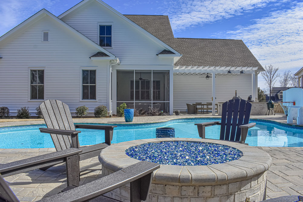 stone fireplace with blue glass installed on poolside patio.