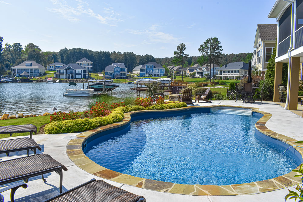 Pool with stone hardscape and a subtle but nice lawn and bushes/shrubs